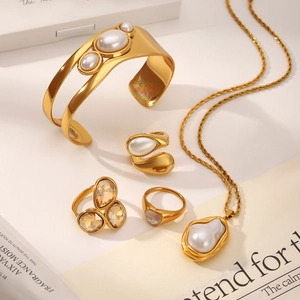 Polished gold jewelry set with baroque pearls and crystal charms on a magazine base