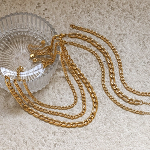 Détail de chaînes Figaro et Gourmette en acier inoxydable plaqué or 18 carats sur pierre