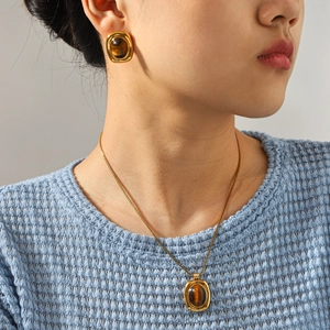 Detail of vintage gold necklace and tiger eye earrings set on a blue knit sweater
