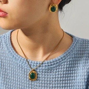Close-up of vintage geometric gold necklace and earrings set with dark green stones