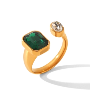 Dettaglio dell'anello in acciaio dorato con pietra verde taglio smeraldo e gemma chiara