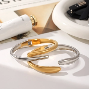 Polished gold and silver wave bangles styled on a tray with modern aesthetic details