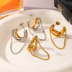 Two-tone C-shape earrings with hanging tassel chains displayed on a ceramic tray