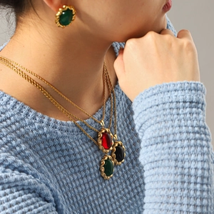 Detail of layered gold rope chains with oval gemstone pendants and matching earrings