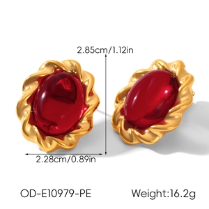 Detail shot of vintage gold earrings with oval red stones and rope texture edges