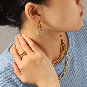 Detalle de pendientes y anillo dorados con diamantes sobre un fondo azul