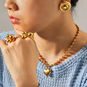 Gepolijste 18k gouden sieradenset met hartjesketting en kralenring op een model