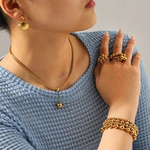 Detail van een 18k vergulde sieradenset met parelketting, oorbellen en een ring