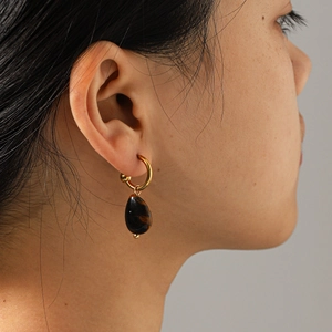 Detailed close-up of a vintage tiger eye stone earring on a model in gold finish