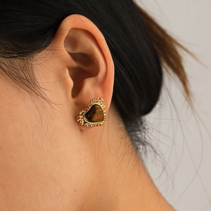 Macro shot of vintage tiger eye heart stud earring with textured gold metal frame on ear