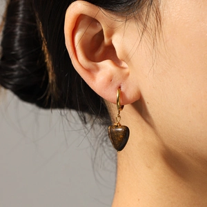 Vintage heart-shaped tiger eye stone earrings with gold hoops on a model, retro style