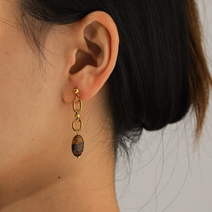 Macro detail of vintage tiger eye stone earring with gold plated polished metal links