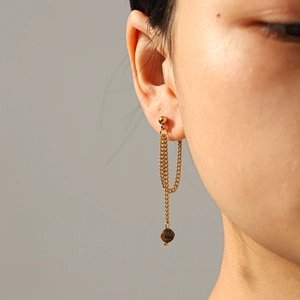 Close-up of vintage golden long tassel earrings with tiger eye stone beads on a model