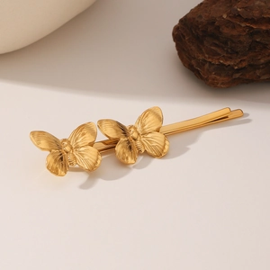 Elegant gold butterfly hair clips with engraved textures on a minimalist base