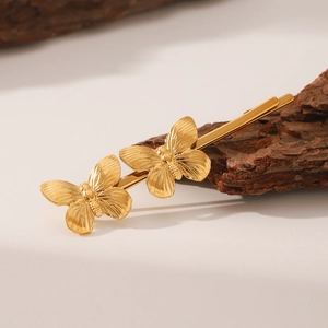 Elegant gold butterfly hair clips featuring detailed wing carvings on natural background