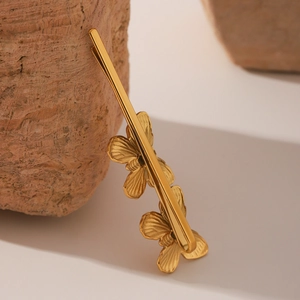 Macro shot of matte gold butterfly hair clips with detailed wing textures on stone