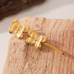 Macro detail of golden butterfly hair clips with intricate wing textures on pink stone