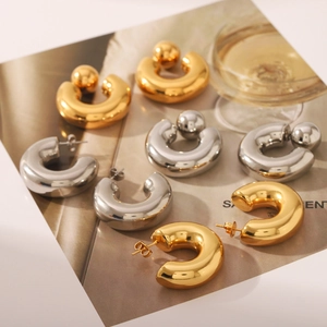 Close-up of thick gold and silver stainless steel hoop earrings on a magazine