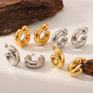 Chunky gold and silver C-shaped hoop earrings on natural wood blocks