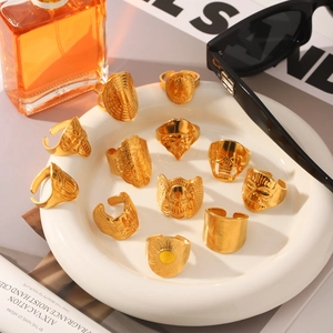 12-teiliges Set goldener Totenkopf- und Adlerringe auf einem weißen Keramikteller