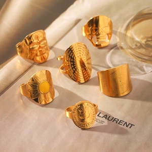 Detailansicht von sechs goldenen Totenkopf- und Münzringen auf einer Modezeitschrift
