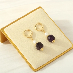Dettaglio orecchino a cerchio in oro 18K con perla bianca e pietra viola sfaccettata