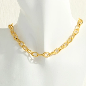 Détail d'un collier chaîne torsadée plaqué or 18K sur un buste blanc d'expo