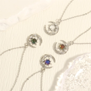 Detalle de cuatro colgantes de luna y estrella con circonitas de colores en plata