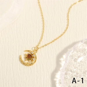Detalle del collar dorado con luna, estrella y circón rojo sobre fondo con textura