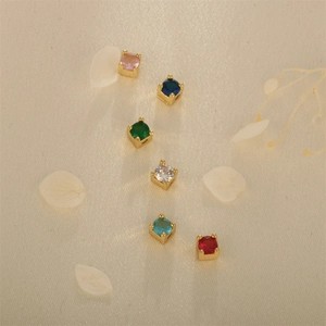 Set of six gold-plated square charms with colorful zircon gemstones on silk background