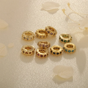 Macro detail of gold-plated rondelle spacer beads with colorful zircon inlay for DIY jewelry
