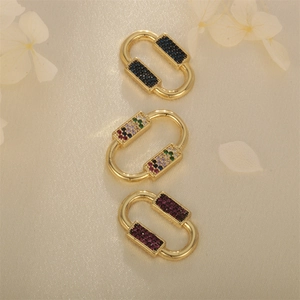 Tre chiusure ovali placcate in oro con zirconi multicolori su tessuto di seta elegante
