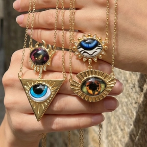 Detail showing four vintage evil eye pendants with diverse colors held in hand