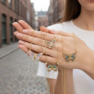 Primer plano detallado de cuatro collares de mariposa con piedras de colores en mano