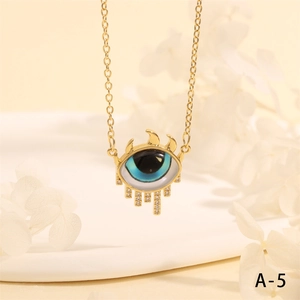 Detail of golden Turkish Evil Eye necklace with blue enamel pendant and tassel with rhinestones