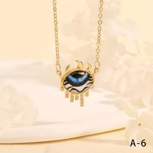 Macro shot of evil eye triangle pendant with blue resin and crystals on gold chain