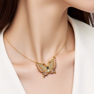 Detalle de un colgante de mariposa con circonitas de colores en un collar dorado fino