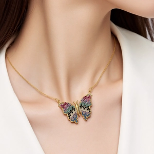Detalle de un collar con colgante de mariposa y circonitas de colores en una modelo