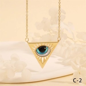 Macro detail of golden triangle evil eye pendant on a chain over a white tray