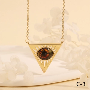 Detail shot of golden triangular evil eye pendant with radial hollow rays and brown stone