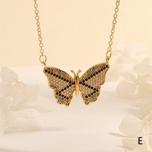 Detalle de un collar dorado con colgante de mariposa y circonitas de colores