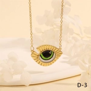 Macro view of gold devil's eye triangle pendant with green inlay on a cross chain