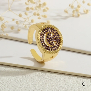Vista macro detallada de un anillo ajustable bañado en oro con logo G de circonitas púrpuras