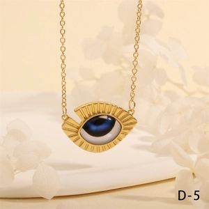Detailed close-up of golden evil eye triangle pendant with blue beads on white tray