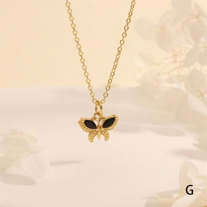 Detail of 18K gold butterfly pendant with black inlay on a delicate chain necklace
