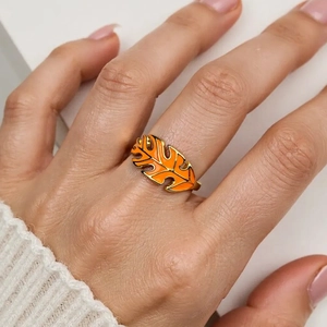 Macro detail of leaf-shaped ring with orange enamel and golden metal lines