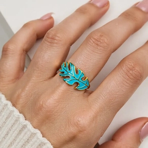 Detailed view of bohemian gold leaf ring with blue enamel worn on a female hand