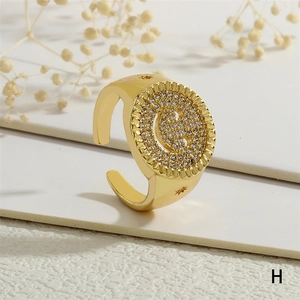 Detalle de anillo dorado con cara sonriente de circonitas y estrellas grabadas en la banda