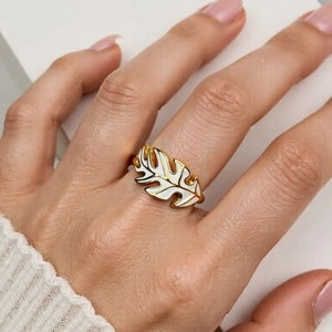 Detail view of a gold leaf ring with white enamel finish worn on a finger