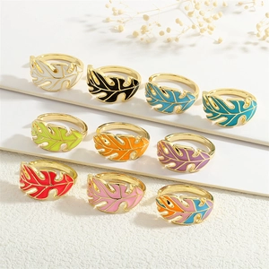 Set of 10 gold monstera leaf enamel rings in various colors with minimalist open design